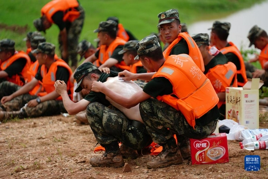 在江西省鄱阳县鄱阳镇江家岭村，武警官兵在休息时互相涂抹药粉，连日奋战让许多战士长痱子或晒伤（2020年7月11日摄）。来自武警江西省总队机动支队的官兵与当地干部，村民一起连续奋战，用沙袋和土石在昌江堤上垒起了一道一米多高，三公里长的临时防水墙。新华社记者 周密 摄